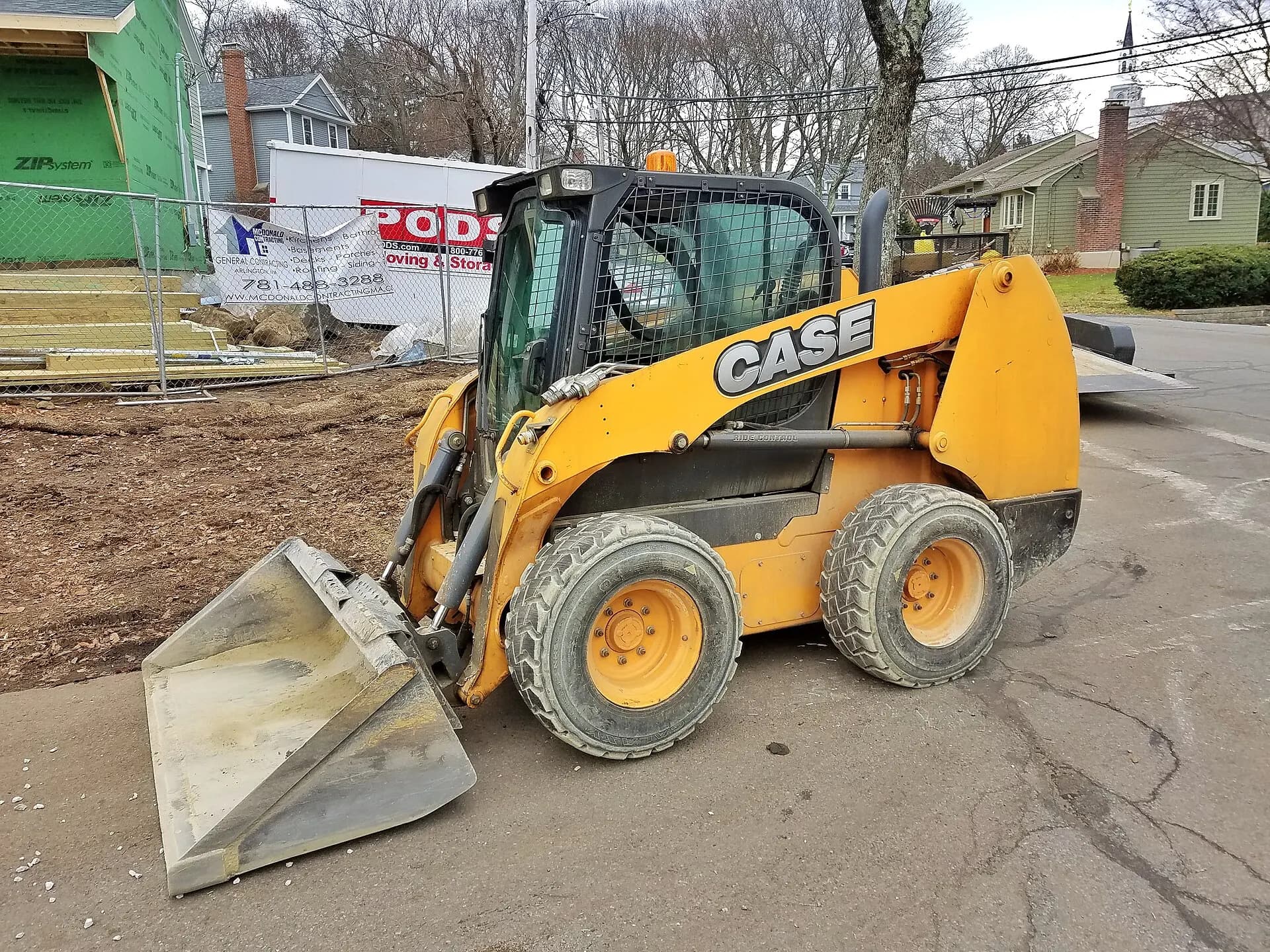 Yellow skid steer loader with bucket on a site